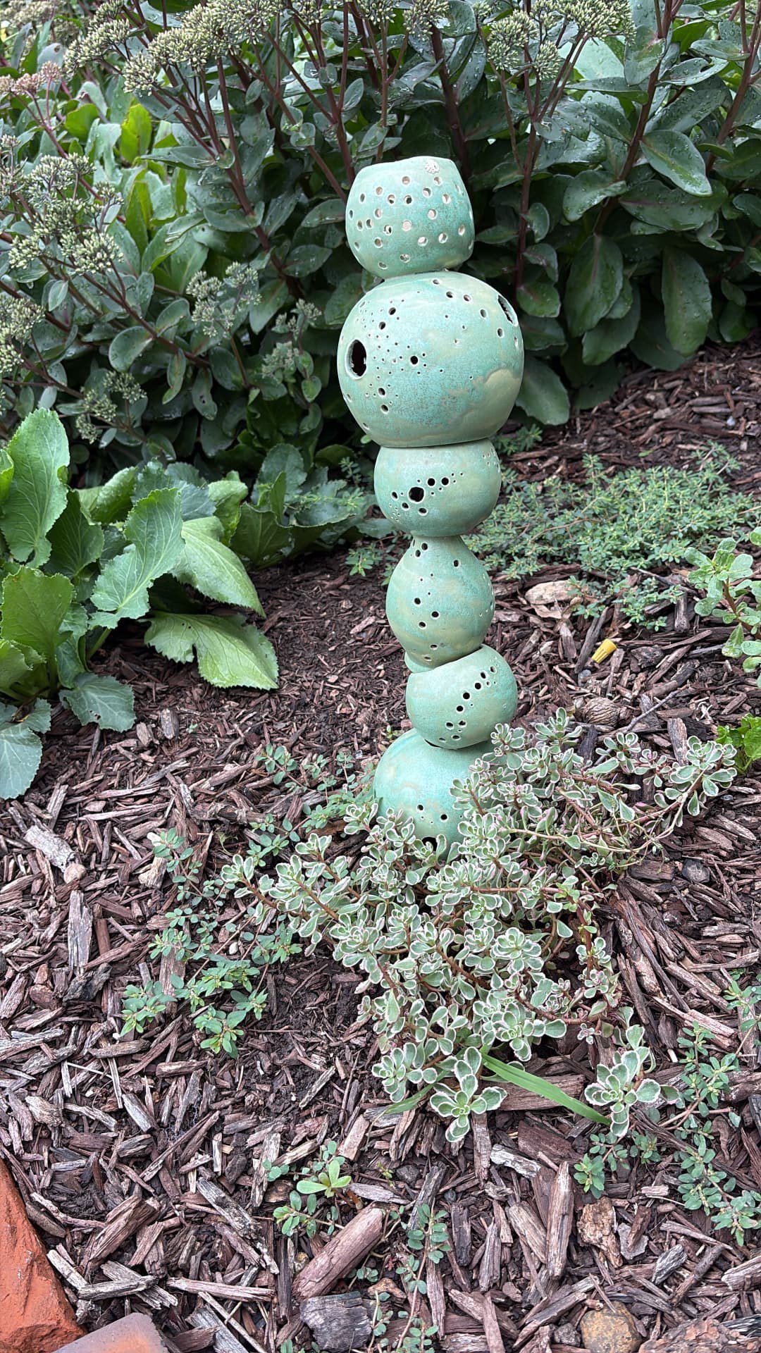 Stacked green perforated ceramic garden sculpture