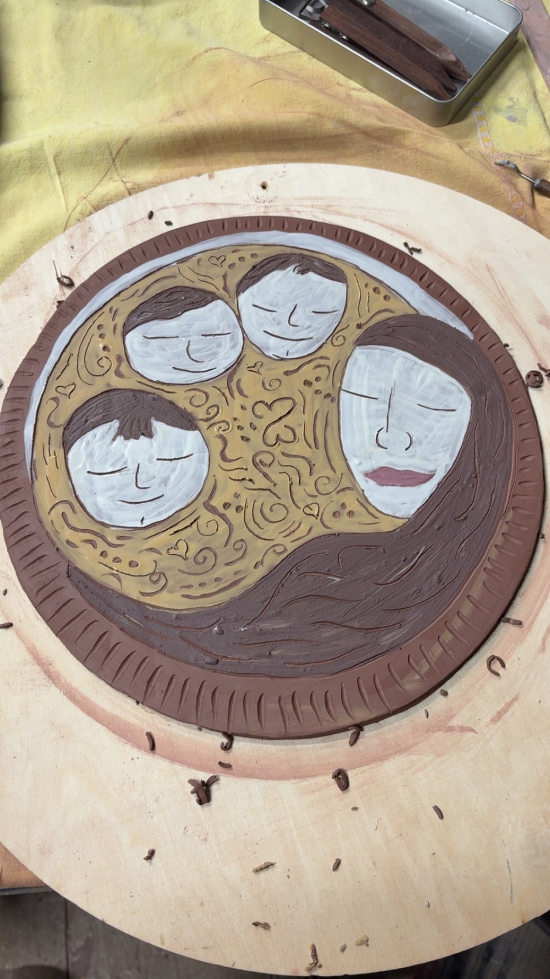 Round clay platter decorated with three painted faces